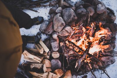 Low section of man standing by bonfire during winter