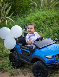Isolated cute toddler with innocent facial expression at toy car at outdoor from different angle