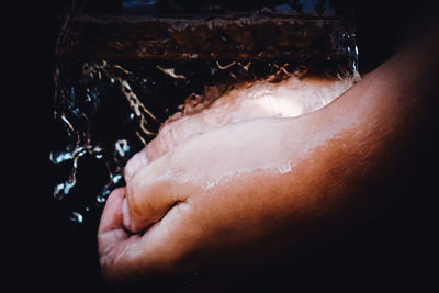 Close-up of hand holding ice cream against black background