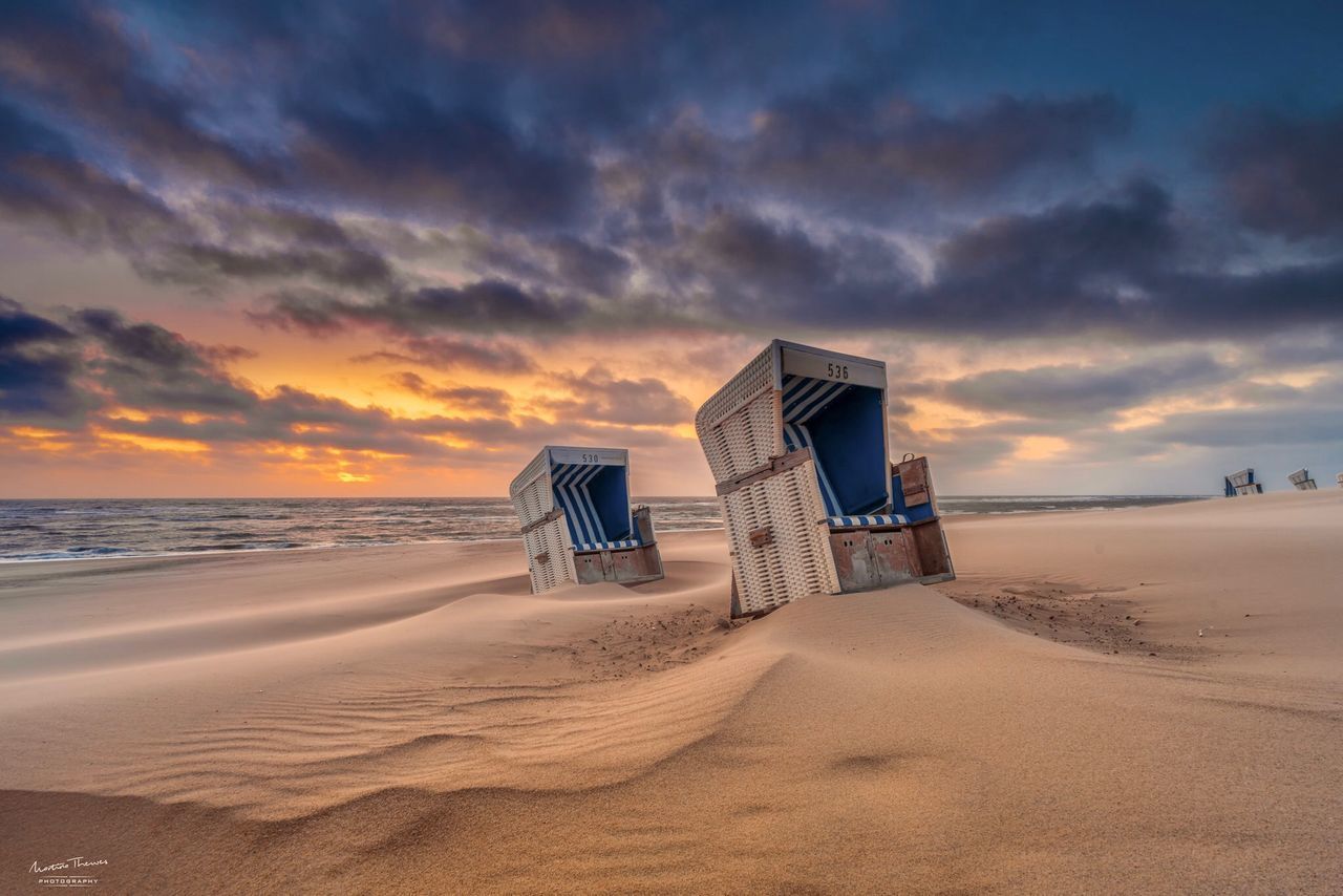 HUT ON BEACH AGAINST SKY DURING SUNSET