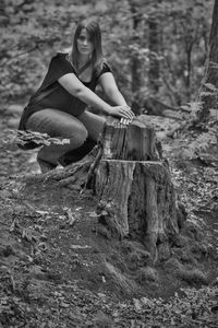 Portrait of young woman sitting on tree trunk