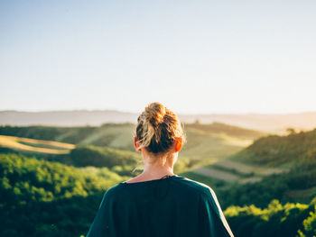 Rear view of blond woman against landscape