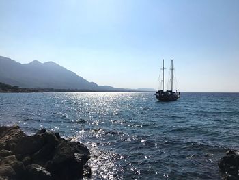 Boat sailing in sea against clear sky