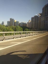 City street by modern buildings against clear sky