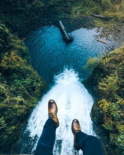 Low section of man sitting above river