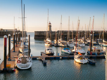 Boats moored in harbor at sunset
