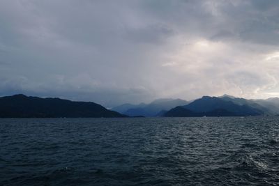 Scenic view of sea by mountains against sky