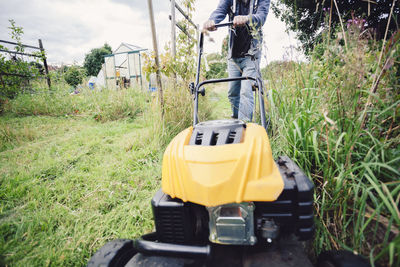 Low section of man mowing lawn