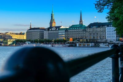 View of buildings by river in city against sky