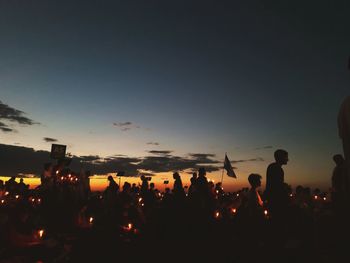 Silhouette people at town against sky during sunset