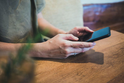 Midsection of man using mobile phone on table