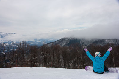 Man with arms raised in winter against sky