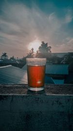 Close-up of beer glass against sunset