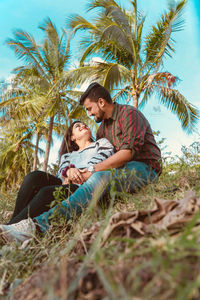 Happy friends sitting on land against trees