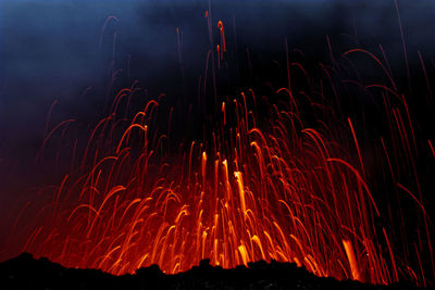 Low angle view of volcanic eruption at night