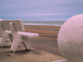 Deck chairs on beach against sky