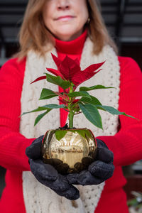 Close-up of woman holding red while standing outdoors