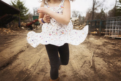 Midsection of girl running on dirt road