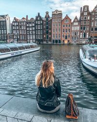 Rear view of woman in boat on canal in city