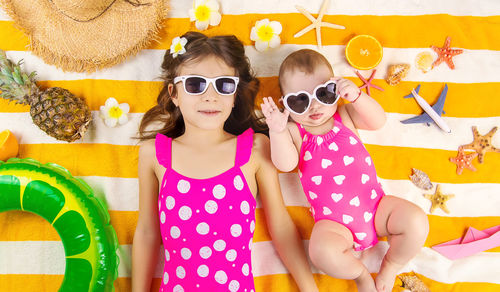 Portrait of smiling woman wearing sunglasses while standing against wall