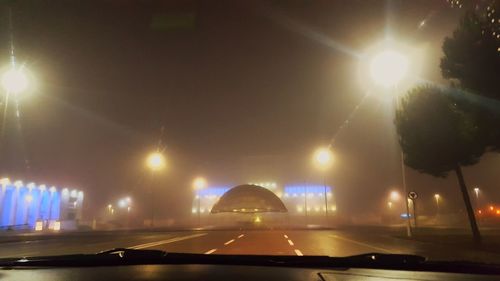 Illuminated cars on road against sky at night