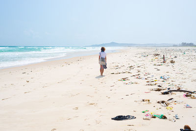 Rear view of man on beach against sky