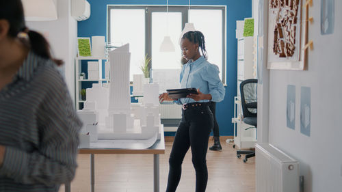 Side view of man using mobile phone while standing in office