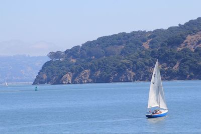 Sailboat sailing on sea by mountain