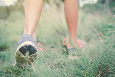 Low section of woman walking on grassy field