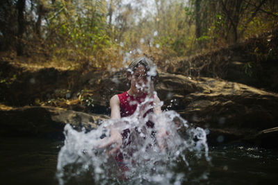 Boy splashing water while enjoying in river