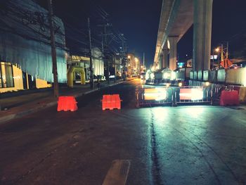 Illuminated street lights by road in city at night