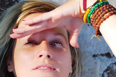 Close-up portrait of beautiful woman shielding eyes against wall on sunny day