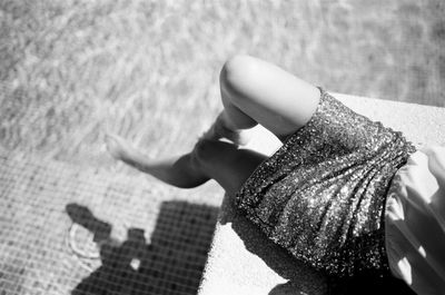 Low section of woman sitting at poolside