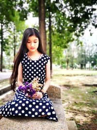 Portrait of young woman sitting in park