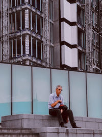 Full length of man sitting outside building