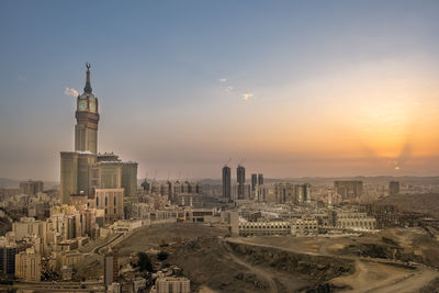 Modern buildings in city against sky during sunset