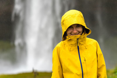 Young female hiker is hiding under the hood from heavy summer rain