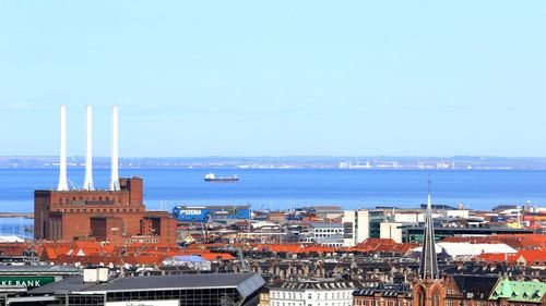 Cityscape by sea against clear sky