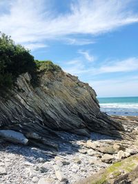 Rock formation on beach against sky