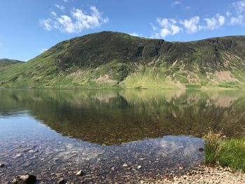 Scenic view of lake by mountains against sky