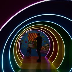 Silhouette people walking in illuminated tunnel