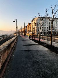 Street amidst buildings against sky during sunset