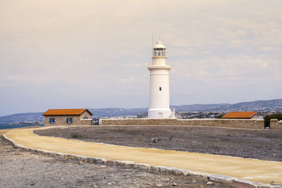 Lighthouse amidst sea and buildings against sky