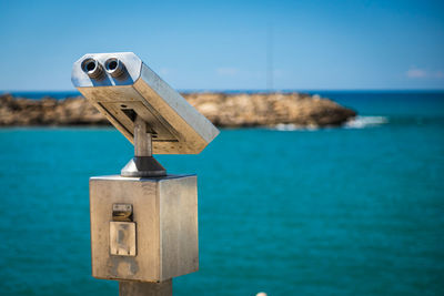 Close-up metal binoculars for public use with views of the beautiful port and sea