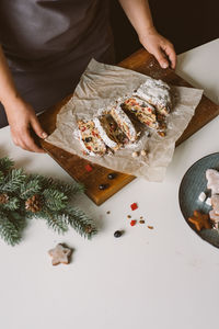 Baker serves christmas pastries, stollen on wooden board.