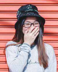 Portrait of beautiful young woman against wall