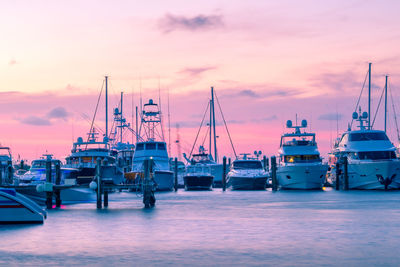 Boats moored at harbor against sky during sunset