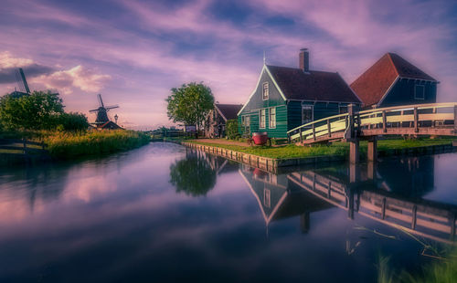 Reflection of houses and trees in lake against sky