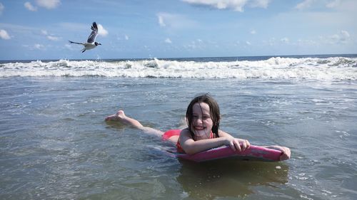 Young woman flying over sea against sky