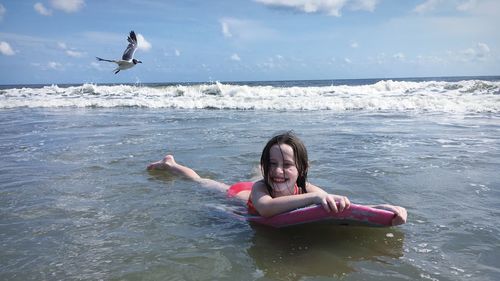 Portrait of cute girl surfing on sea at beach